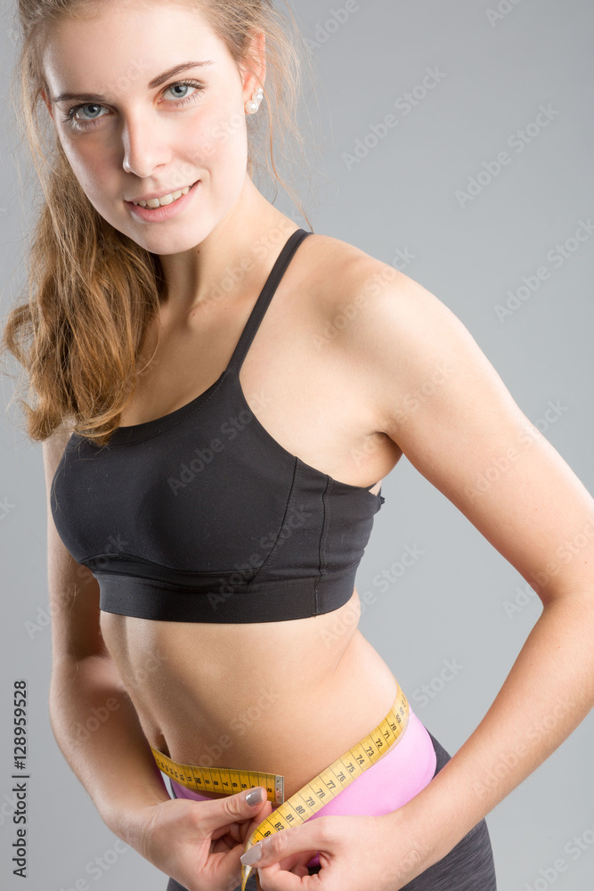 Fototapeta premium Mädchen im Sportoutfit misst sich die Taille