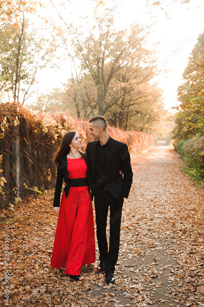 Young couple of pretty girl and man walk outdoors in park on aut Young couple of pretty girl and man walk outdoors in park on aut
