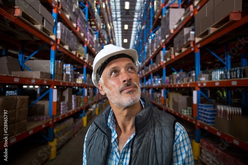 Warehouse worker looking at cardboard boxes on shelves