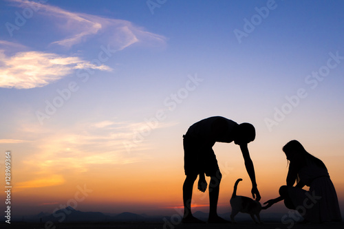 Silhouette of Happy Young Couple playing with cat Outside at Sunset © max_play