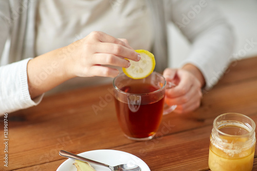 close up of ill woman drinking tea with lemon