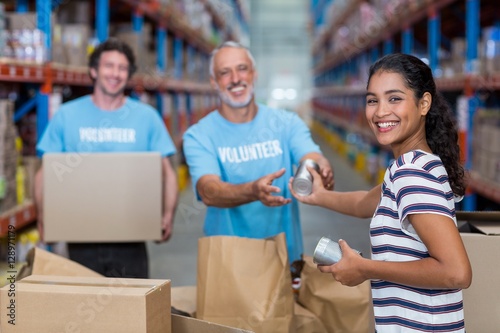 Three volunteers packing eatables in cardboard box © WavebreakMediaMicro