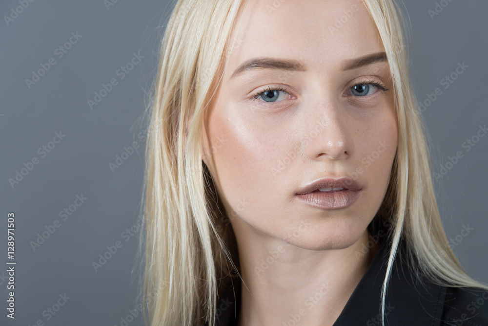Fototapeta premium Portrait of a blond girl in a leather jacket gray studio backgro