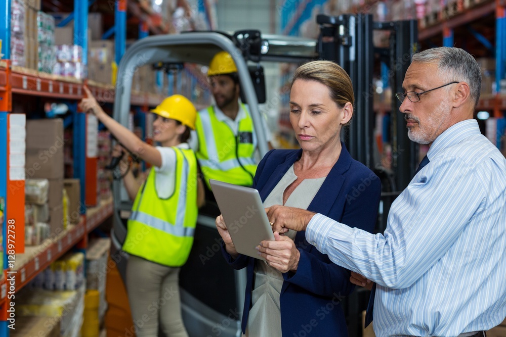 Warehouse manager and client discussing over digital tablet Warehouse manager and client discussing over digital tablet