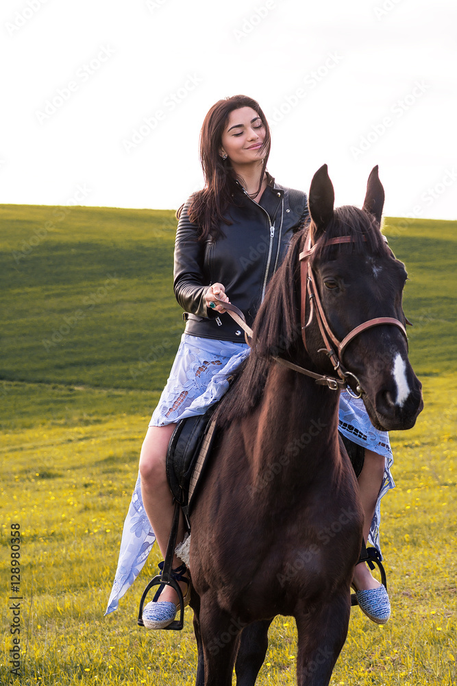 Obraz premium beautiful young woman riding a horse in a meadow