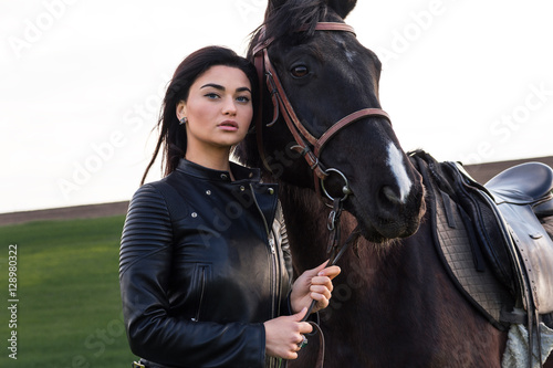 beautiful young woman walking with a horse in a meadow