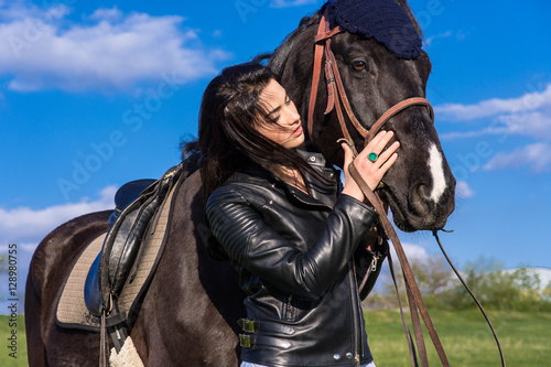 beautiful young woman walking with a horse in a meadow