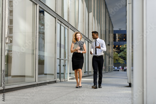 Business colleagues walking along the office building © sata_production