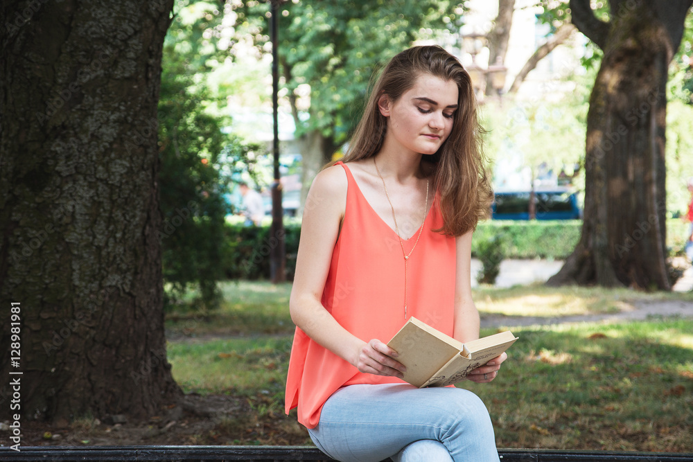 Obraz premium Slim young girl, sitting and reading a book, background, on th