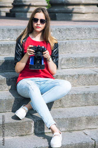 beautiful young woman using a vintage camera in the street at su