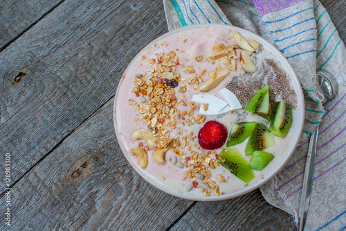 Banana-strawberry smoothie with kiwi, chia, muesli with nuts and coconut in a bowl. Perfect for the detox diet or just a healthy meal.  Love for a healthy raw food concept.