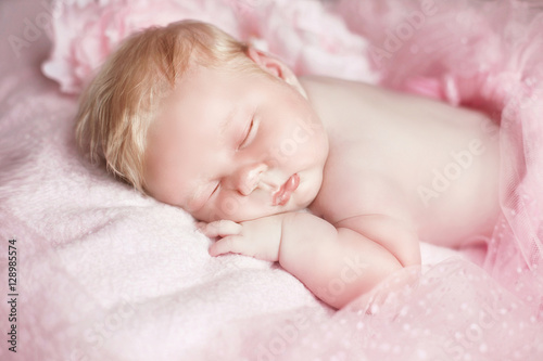 Portrait of adorable sleeping baby girl over pink, infant child.
