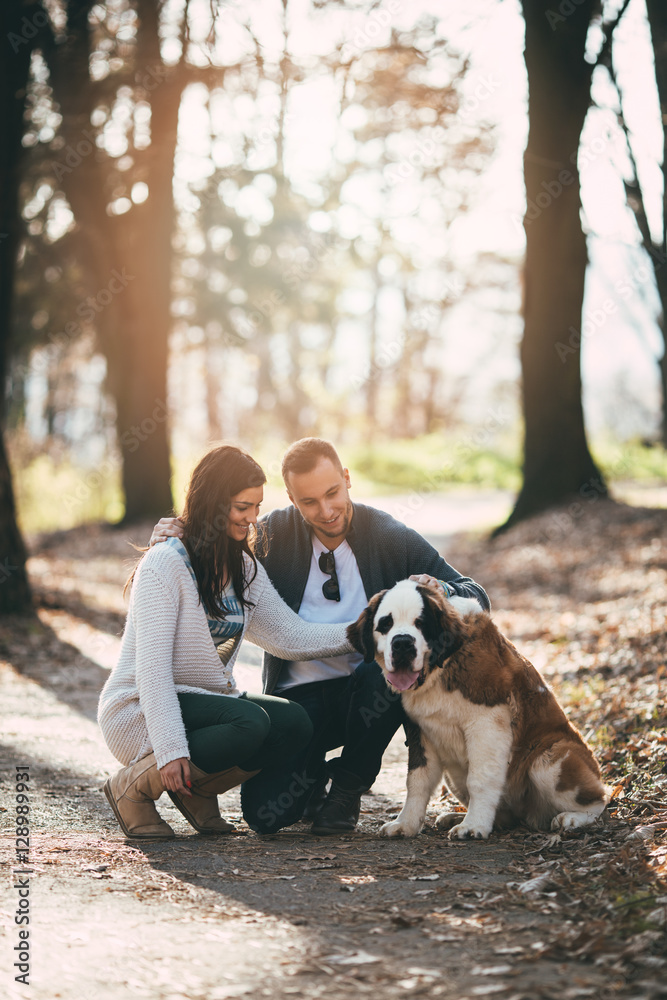 People and dogs. Young couple enjoying nature or park outdoors together with their adorable Saint Bernard puppy. People and dogs. Young couple enjoying nature or park outdoors together with their adorable Saint Bernard puppy.