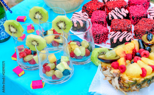 Champagne with fruit in a beautiful glass. Colorful Cakes on the occasion. Picnic table.
