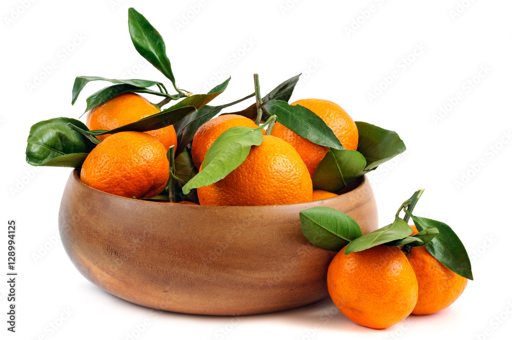 Fresh tangerines with green leaves in a wooden bowl