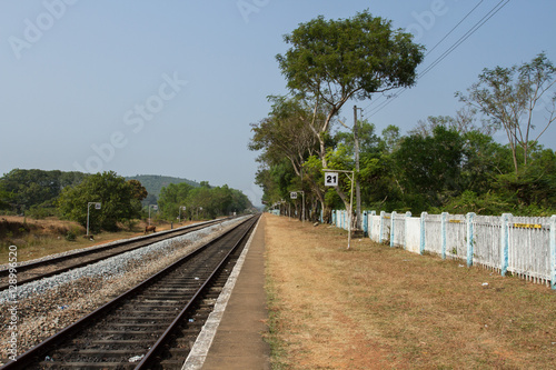 Railway platform with a tree and white fence