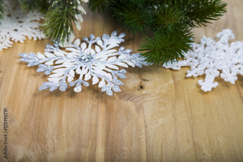 Silver snowflakes and fir branches on a wooden table. Christmas
