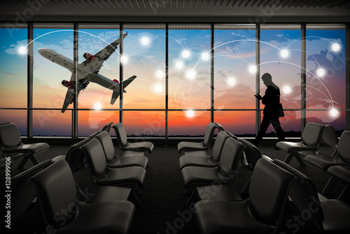 Silhouetted of businessman use mobile phone in airport at sunset