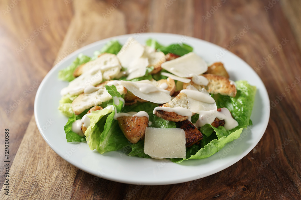 caesar salad with chicken on old wooden table, shallow focus