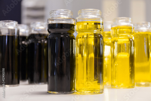 Bright yellow olive oil and black balsamic vinegar on the restaurant kitchen table. A lot of bottles with two foreground. Bottling of dressing.