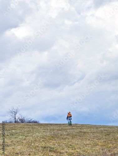 Lonely hiker is walking thru mountain with rainy clouds above him