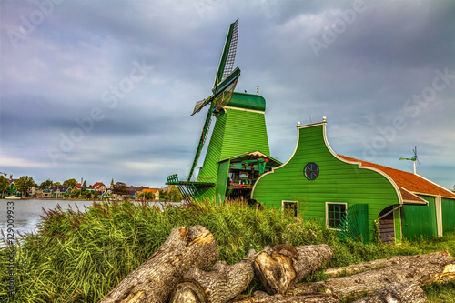Dutch village with a green windmill and overcast skies after rain, HDR Image.