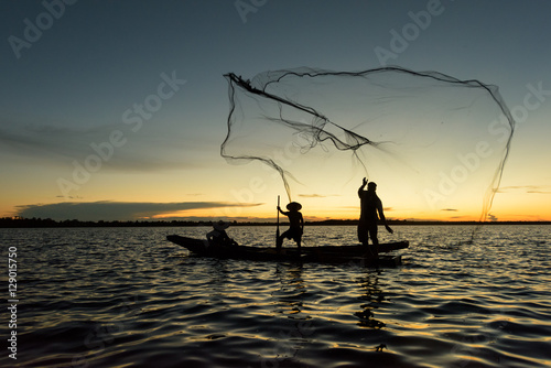 Silhouette of traditional fisherman throwing net fishing lake at