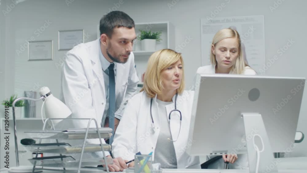 Three Doctors Discuss Medical Issues while Consulting Personal Computer. Shot on RED Cinema Camera in 4K (UHD). Three Doctors Discuss Medical Issues while Consulting Personal Computer. Shot on RED Cinema Camera in 4K (UHD).