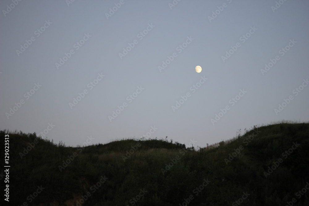 Twilight and dusk sky. Dark hills and bright moon on clean sky. Twilight and dusk sky. Dark hills and bright moon on clean sky.