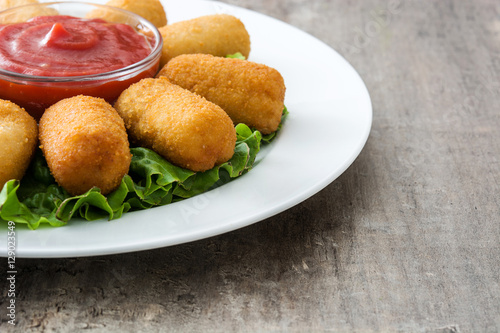 Traditional fried Spanish croquetas (croquettes) with ketchup in plate on wooden background
