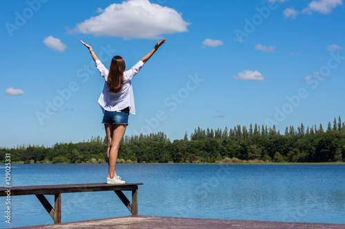 Happy woman with her arms outstretched enjoying on the bench by the pool. photo