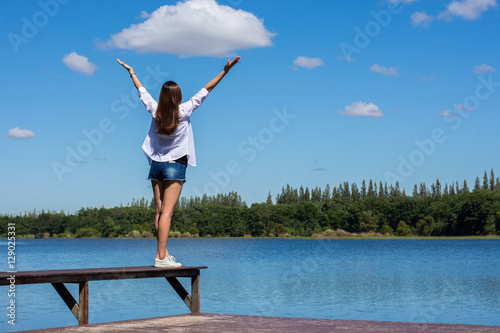 Vászonkép Happy woman with her arms outstretched enjoying on the bench by the pool
