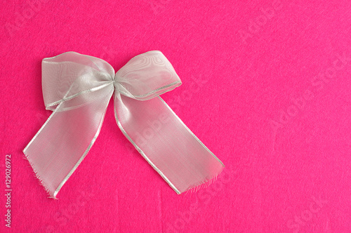 A silver bow isolated against a pink background