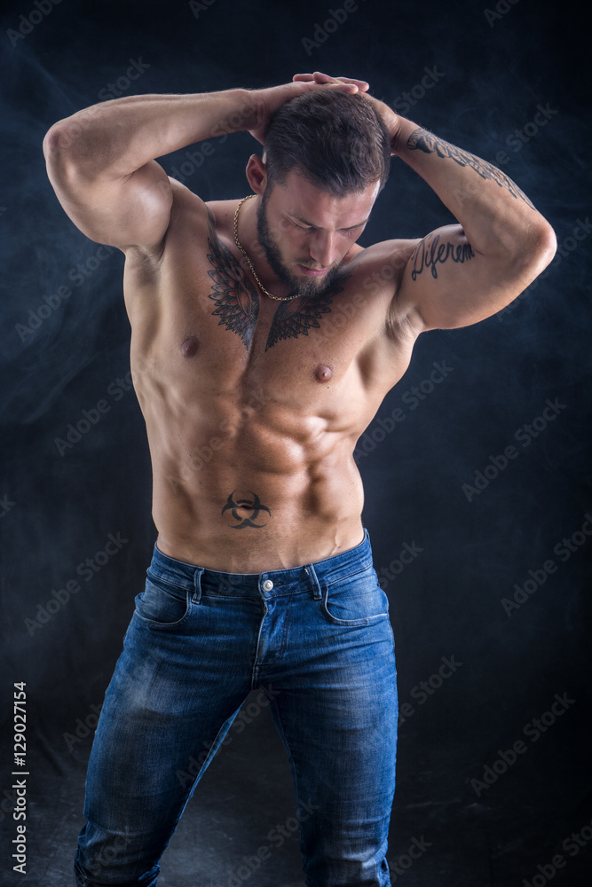 Handsome shirtless muscular man with jeans, standing, on black background Handsome shirtless muscular man with jeans, standing, on black background