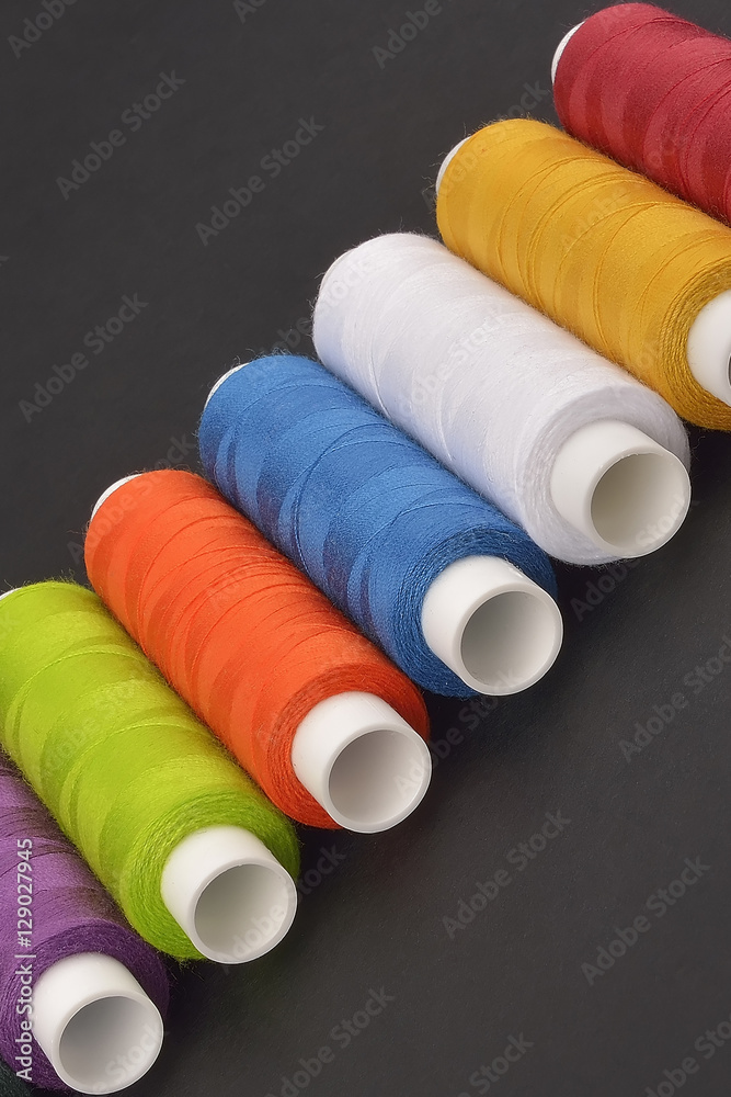 colorful spools thread on dark background colorful spools thread on dark background