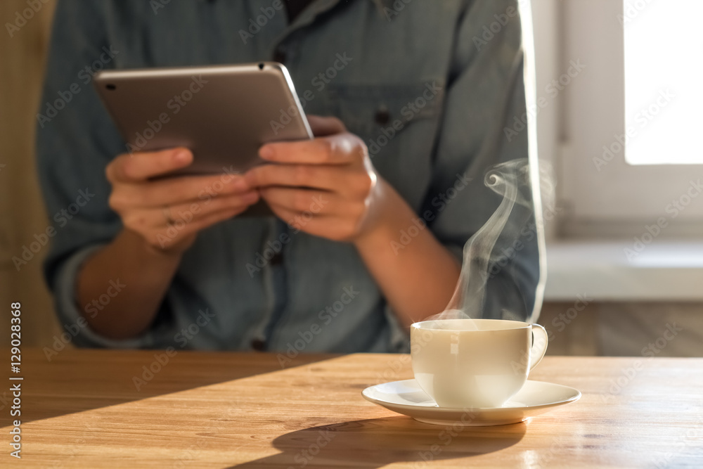 Checking email at breakfast. Person uses tablet PC to surf internet while drinking morning coffee at home kitchen Checking email at breakfast. Person uses tablet PC to surf internet while drinking morning coffee at home kitchen