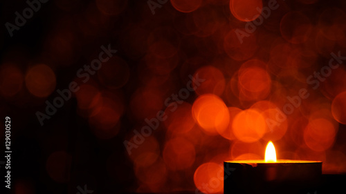 Candle flame light at night with abstract circular bokeh background Christmas lights.