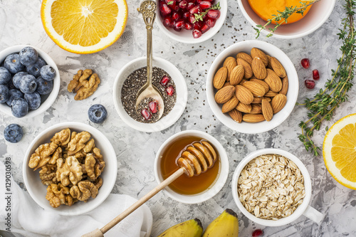 Ingredients for a healthy breakfast, nuts, oatmeal, honey, berries, fruits, blueberry, orange, pomegranate seeds, almonds, walnuts The concept of natural organic food in season Top
