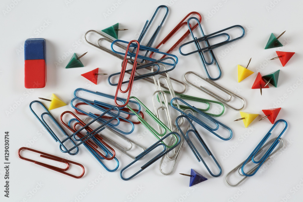 colored paper clips, buttons and eraser on a white background colored paper clips, buttons and eraser on a white background