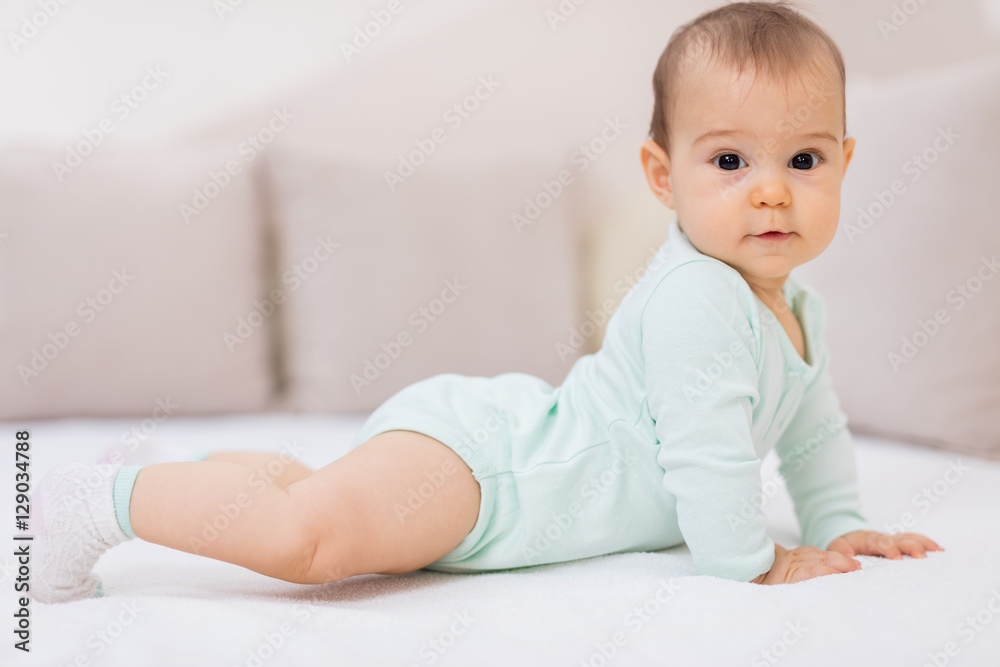 Baby girl on white bed / Cute baby girl lying on her tummy