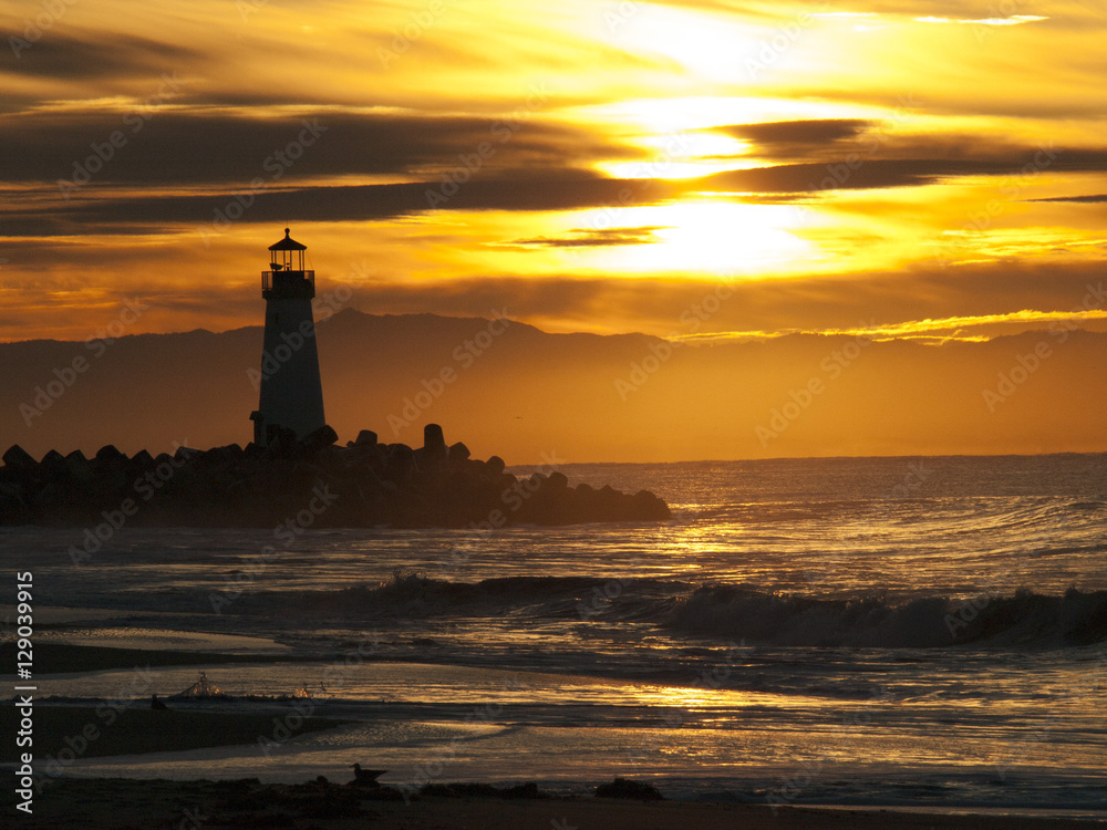Lighthouse in Sunrise rays with Waves