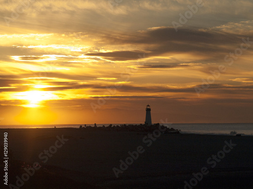 Distant lighthouse backlit by sunrise