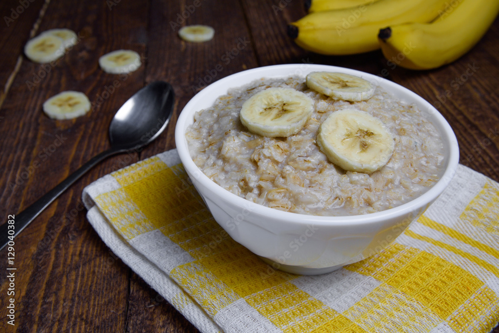 oatmeal in a beautiful white bowl on a warm wooden background with slices of bananas oatmeal in a beautiful white bowl on a warm wooden background with slices of bananas