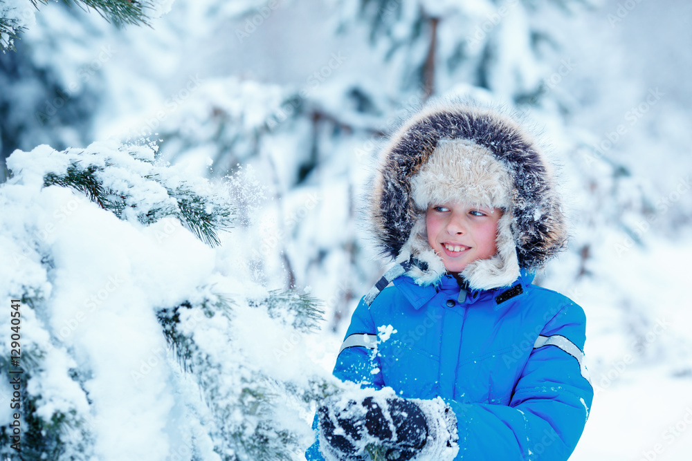 Cute little boy wearing warm clothes playing on winter forest Cute little boy wearing warm clothes playing on winter forest