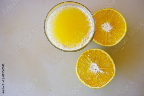 A glass of freshly squeezed tangerine juice with tangerines cut in half