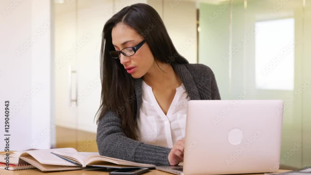 A college student does her homework on her laptop in the library A college student does her homework on her laptop in the library