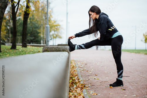 Woman runner stretching legs before run.
