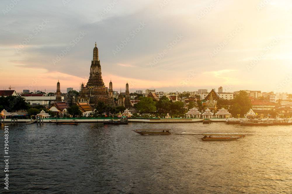 Wat Arun during sunset woth longtail boat in Chao Phraya river a