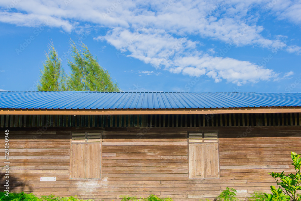 The old wooden building roofed with blue sheet metal roofs and sky background. The old wooden building roofed with blue sheet metal roofs and sky background.