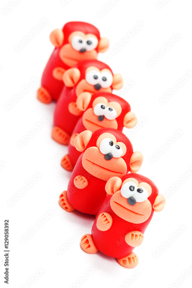 Row of clay toys (monkeys). Isolated on white background, tilted Row of clay toys (monkeys). Isolated on white background, tilted